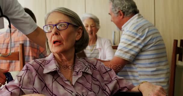 Врач на коленях, разговаривая с инвалидом пожилой женщины — стоковое видео