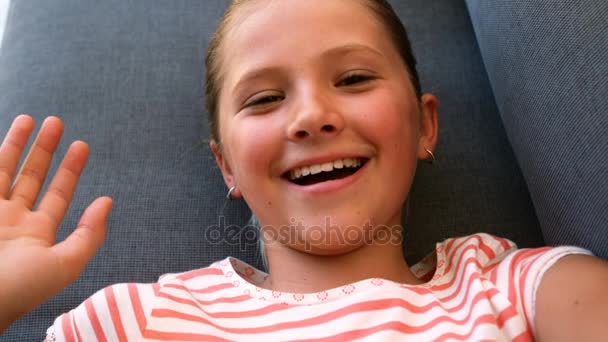 Portrait of cute girl waving hand on sofa — Stock Video