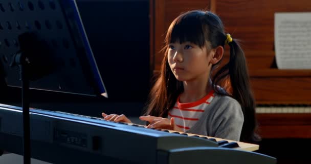 Школьница учится играть на электрофортепиано на уроке музыки — стоковое видео