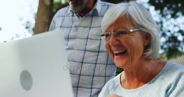 Щаслива старша жінка використовує ноутбук в саду — стокове відео