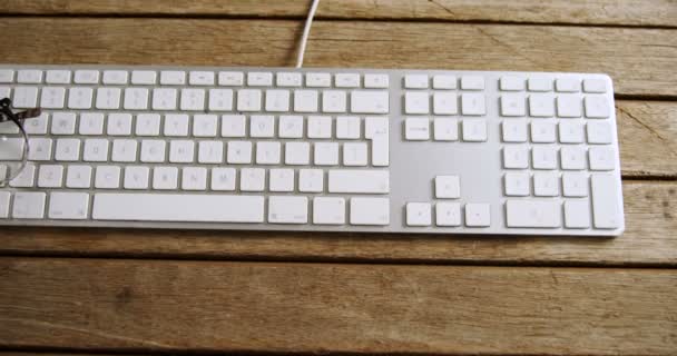 Spectacles and keyboard on wooden table — Stock Video