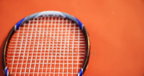 Теннисный мяч, браслет и ракетка на красном полу — стоковое видео