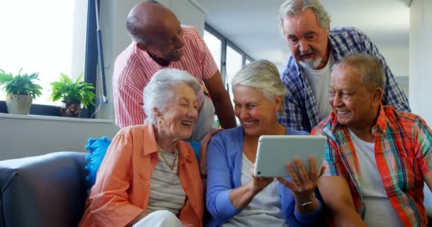 Amigos seniores felizes usando tablet digital no sofá — Vídeo de Stock