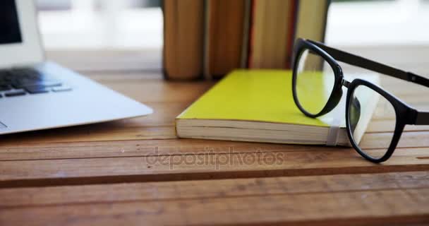 Notebook, knihy a brýle na dřevěný stůl — Stock video