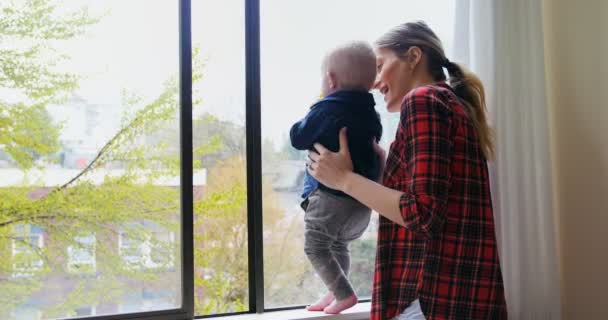 Mãe com seu bebê de pé perto da janela — Vídeo de Stock