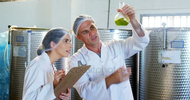 Técnicos escribiendo en el portapapeles mientras examinan el aceite de oliva — Vídeos de Stock