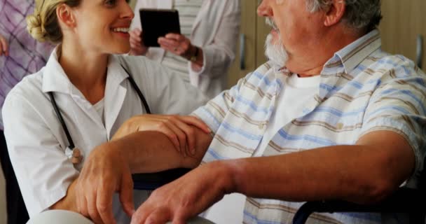 Médico ajoelhado enquanto conversa com o homem idoso com deficiência — Vídeo de Stock