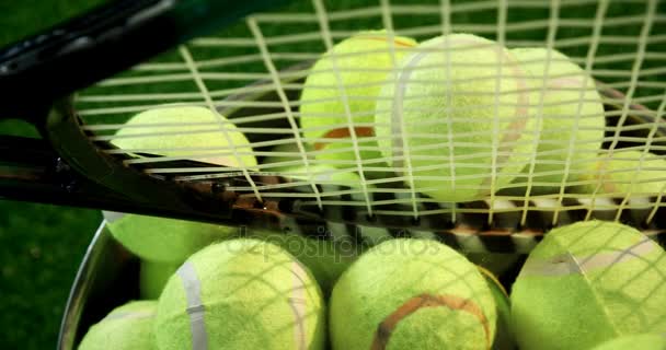Pelotas de tenis y raqueta en cubo en el estudio — Vídeos de Stock