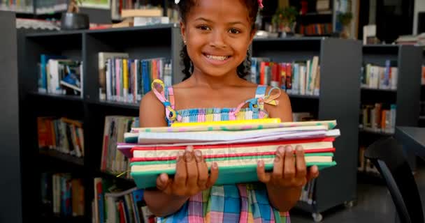 Colegiala feliz de pie con pila de libros — Vídeos de Stock