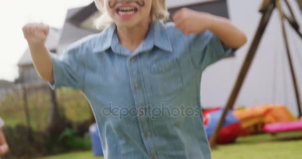 Счастливый мальчик с краской для лица прыгает на заднем дворе — стоковое видео