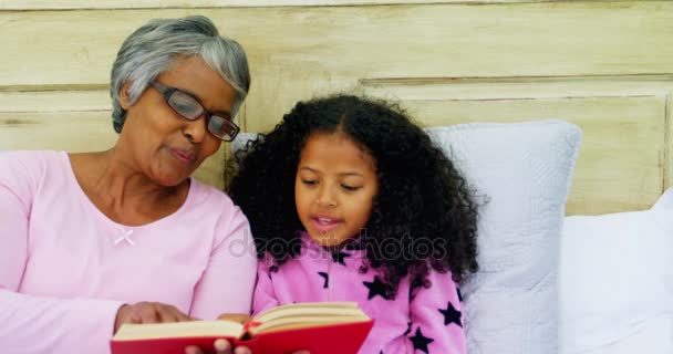 Grandmother and daughter reading book on sofa — Stock Video