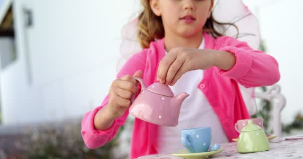 Mädchen im Feenkostüm gießt Tee in Tasse — Stockvideo