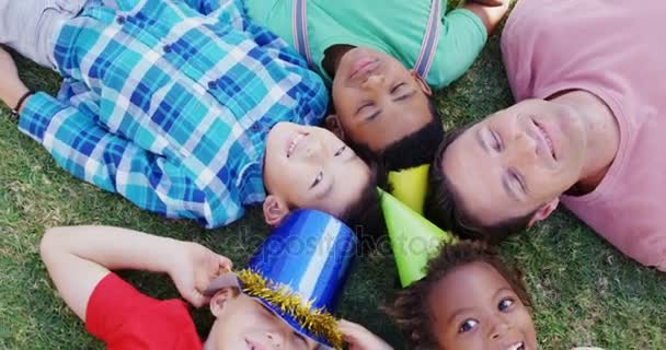 Человек с детьми лежит на поле — стоковое видео
