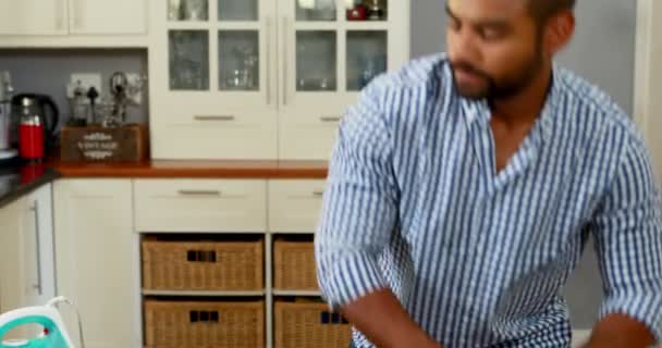 Mann bügelt Kleidung in Küche — Stockvideo