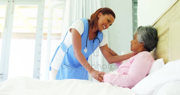 Kvinnliga läkare tröstande senior kvinna på sängen — Stockvideo