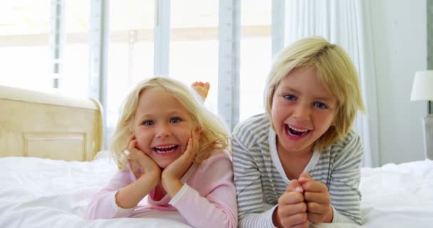 Счастливые братья и сестры отдыхают на кровати в спальне — стоковое видео