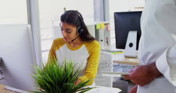 Executivo com fones de ouvido usando computadores na mesa no escritório 4k — Vídeo de Stock