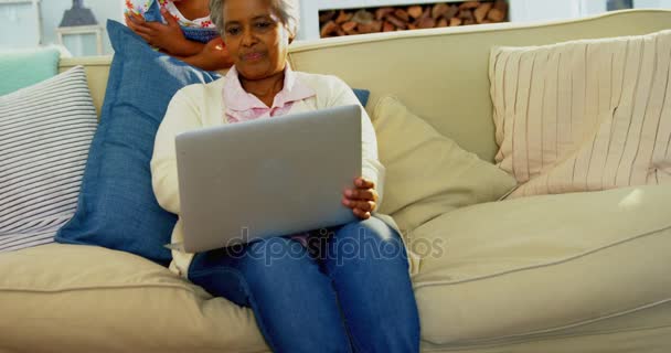 Γιαγιά και εγγονή που χρησιμοποιούν φορητό υπολογιστή στο σαλόνι — Αρχείο Βίντεο