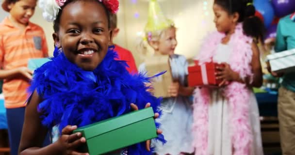 Κοπέλα που κρατά μια συσκευασία δώρου κατά τη διάρκεια της γενέθλια πάρτι στο σπίτι — Αρχείο Βίντεο