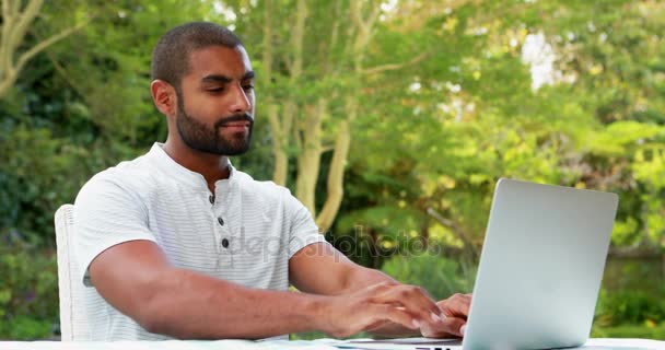 Χαμογελαστός άνθρωπος που χρησιμοποιούν φορητό υπολογιστή στον κήπο — Αρχείο Βίντεο