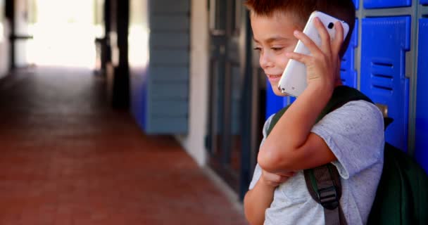 Heureux écolier parler sur téléphone mobile dans couloir — Video