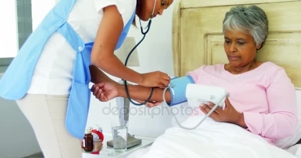 Médico midiendo la presión arterial de la mujer mayor — Vídeo de stock