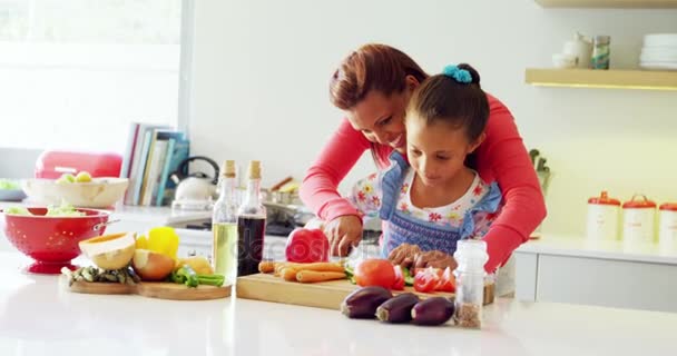 Mãe assistente filha para cortar legumes na cozinha — Vídeo de Stock