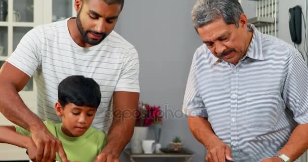 Abuelo y padre ayudando a un niño a cortar verduras — Vídeo de stock