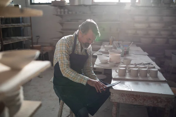 Мужской гончар с помощью цифрового планшета на рабочем столе — стоковое фото