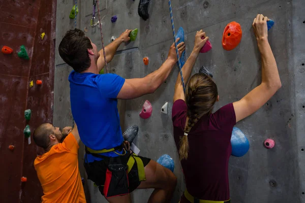 Athletes with trainer climbing wall in gym — Stock Photo, Image