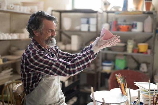 Hombre alfarero mirando cuenco pintado — Foto de Stock