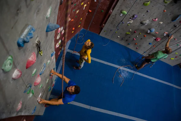 Atletas que examinan la pared de escalada en el gimnasio — Foto de Stock