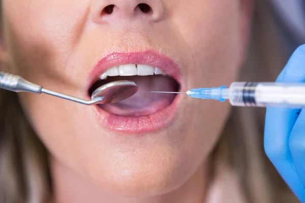 Dentiste tenant la seringue par la bouche du patient — Photo