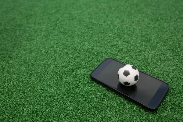 Fútbol y teléfono móvil en césped artificial —  Fotos de Stock