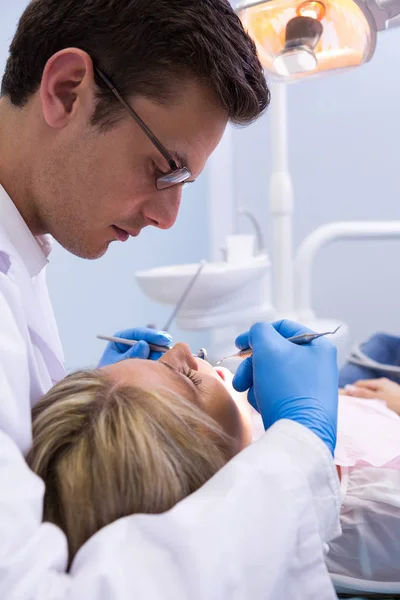 Dentista examinando mulher com equipamentos odontológicos — Fotografia de Stock