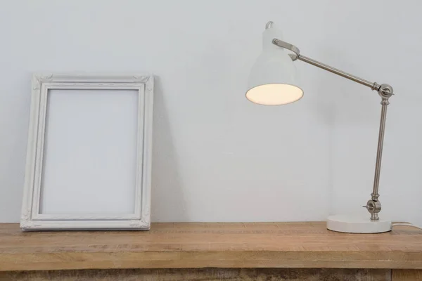 Картинна рамка та освітлена лампа на столі — стокове фото