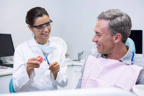 Dentist teaching man brushing teeth — Stock Photo, Image