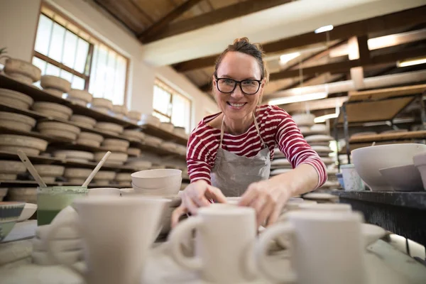 Woman checking mugs at worktop — Stock Photo, Image