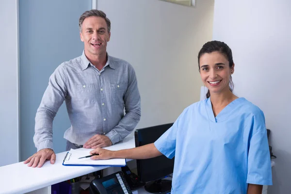 Cheeful doctor and man standing at desk — Stock Photo, Image