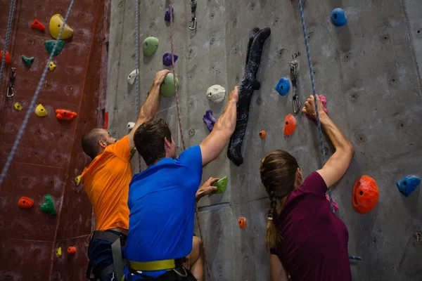 Athletes and trainer climbing wall in gym — Stock Photo, Image