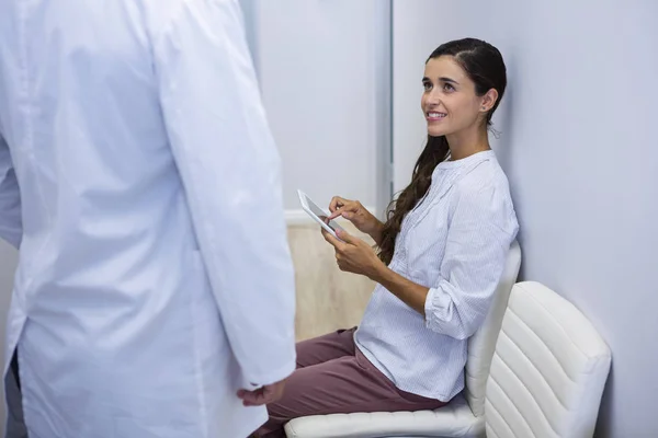 Mujer sosteniendo la tableta mirando al dentista — Foto de Stock