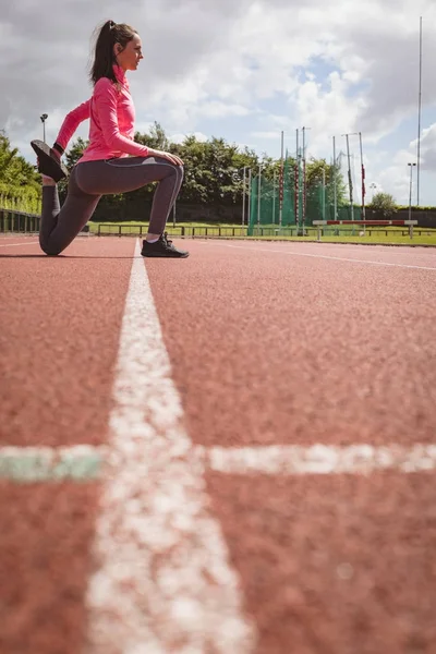 Mulher realizando exercício de alongamento na pista de corrida — Fotografia de Stock