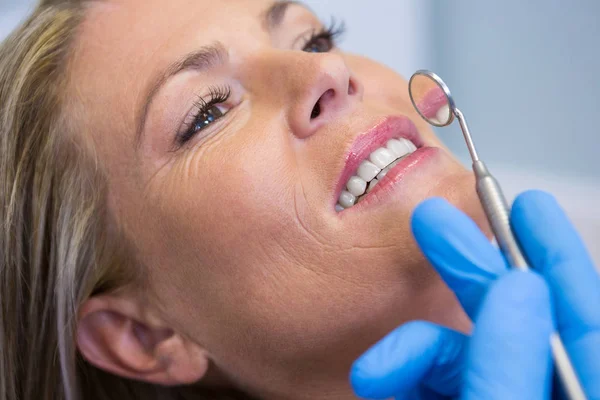 Dentista sosteniendo espejo en ángulo por mujer —  Fotos de Stock