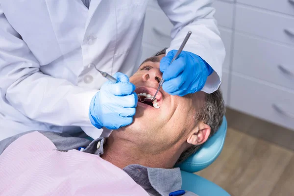 Dentista que dá tratamento odontológico ao homem — Fotografia de Stock