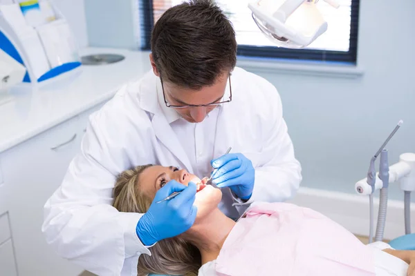 Dentista examinando mulher com equipamentos — Fotografia de Stock