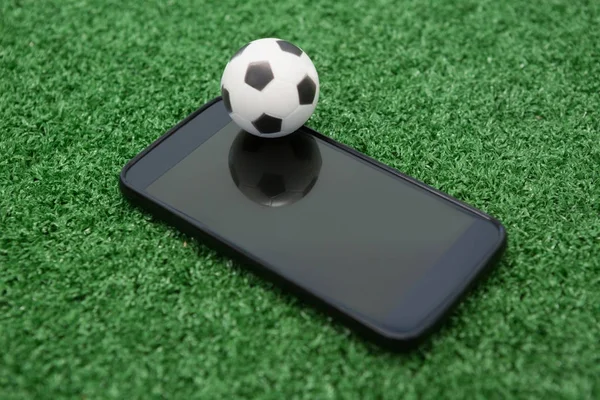 Fútbol y teléfono móvil en césped artificial — Foto de Stock