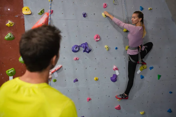 Uomo che interagisce con la parete da arrampicata atleta femminile — Foto Stock