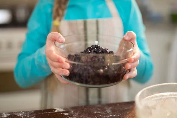 Menina segurando tigela de bagas azuis secas na cozinha — Fotografia de Stock