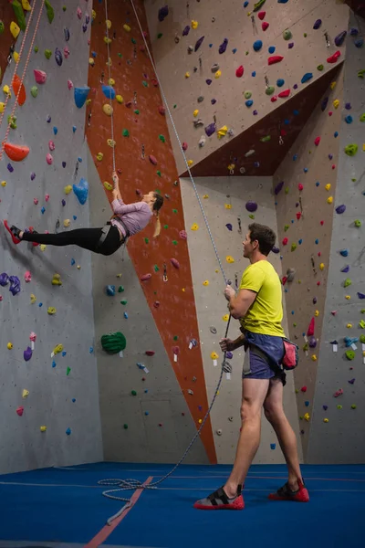 Чоловік тримає мотузку, дивлячись на скелелазну стіну спортсмена — стокове фото