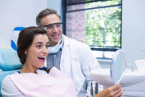 Женщина смотрит в зеркало стоматолога — стоковое фото